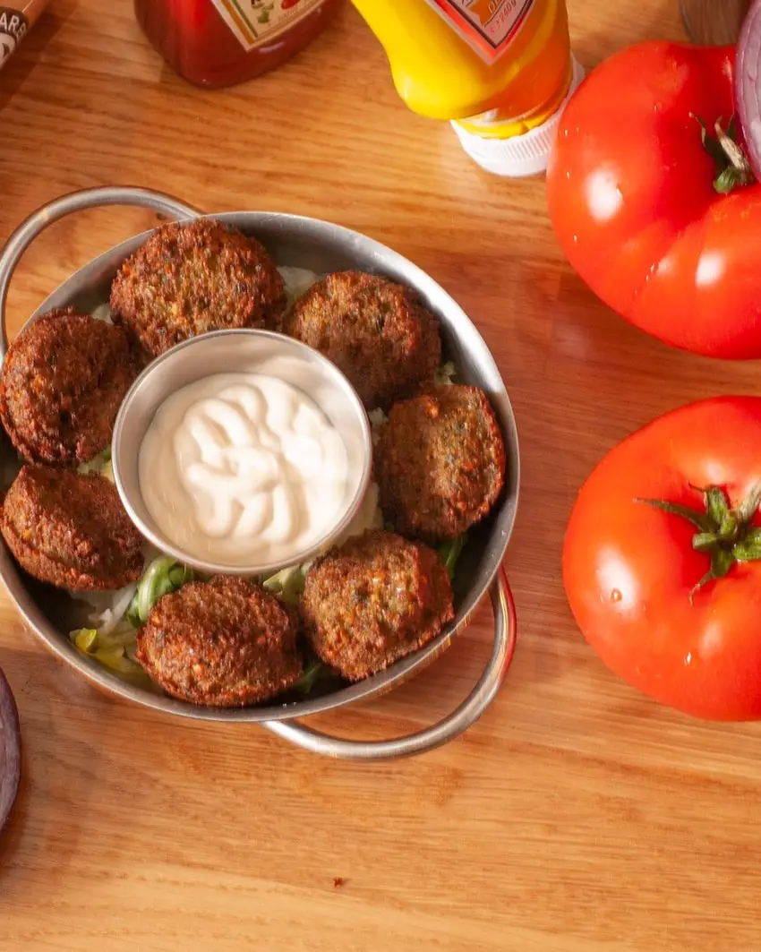 Falafel recién frito en cazuela metálica, con salsa de yogur en el centro