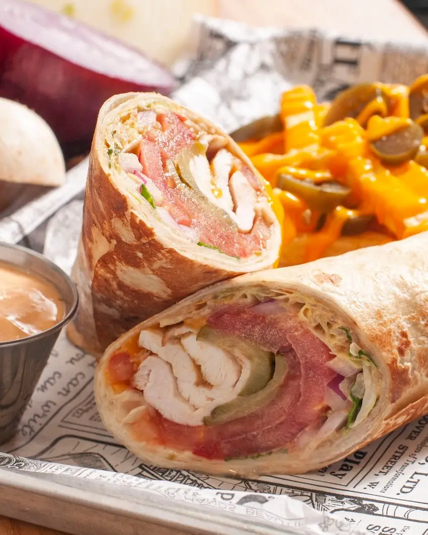 Wrap de pollo y pavo cortado por la mitad, con patatas cubiertas de queso fundido y jalapeños